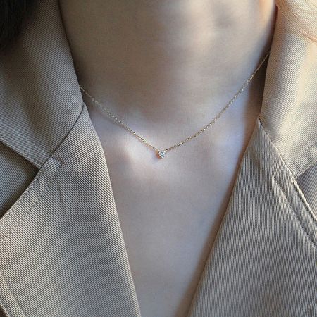 Close-up view of the delicate gold chain and small, elegant pendant.