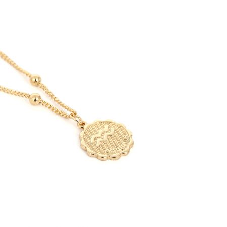 The textured surface of the gold zodiac pendant necklace.