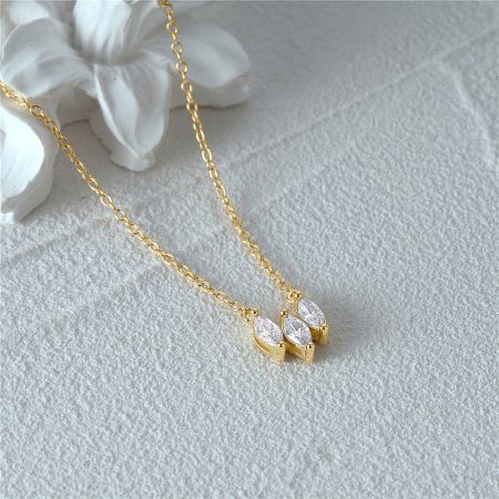Another perspective of the gold necklace with three clear zircon gemstones.
