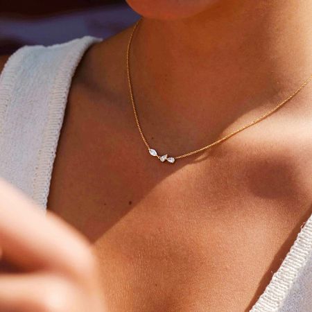 Detailed view of the gold necklace highlighting the three brilliant white zircon gemstones in a curved setting.