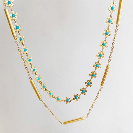 The stainless steel necklace coiled to display its intricate floral pattern with turquoise accents.