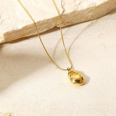 Close-up of the stainless steel hollow oval pendant necklace on a marble surface.