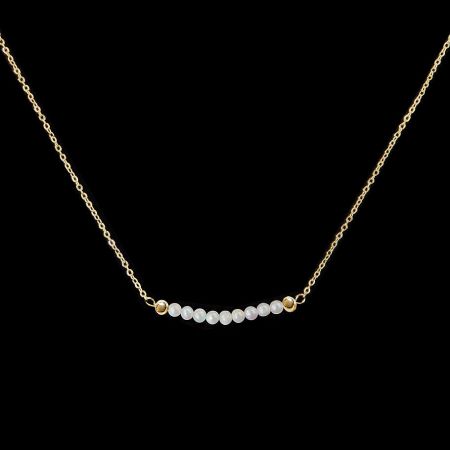 Detailed view of the gold chain necklace featuring lustrous white freshwater pearls.