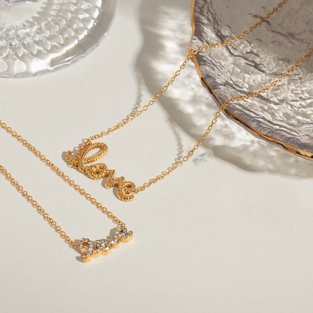 A flat lay of the gold 'Love' pendant necklaces, showcasing the delicate design.