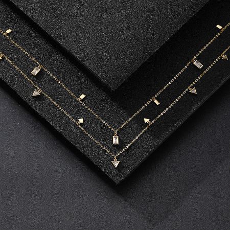 Two geometric charm necklaces presented in a black jewelry box, highlighting their elegant design.