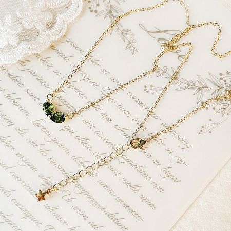 A collection of gold-plated necklaces including the green heart pendant and a star pendant.