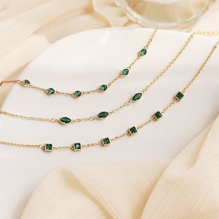 Close-up of three gold-plated sterling silver bracelets, each featuring a different green gemstone shape: square, eye, and heart.