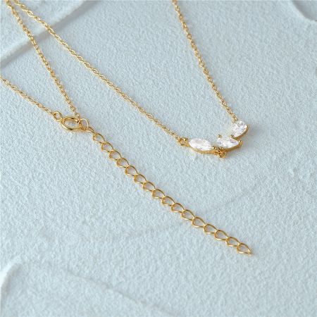 The gold necklace laid flat to show the full length of the chain and the intricate pendant design.