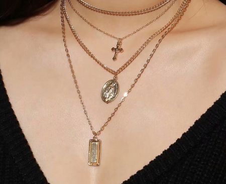 A collection of custom gold religious pendant necklaces with various designs.