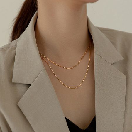 A model elegantly wearing the gold snake chain necklaces from the set.