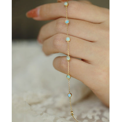 A hand holding the delicate opal chain bracelet to display its craftsmanship.