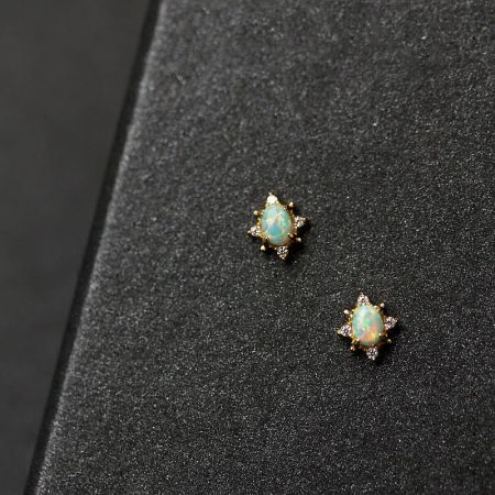 Elegant opal and diamond earrings with a gold setting, displayed on a luxurious black velvet background.