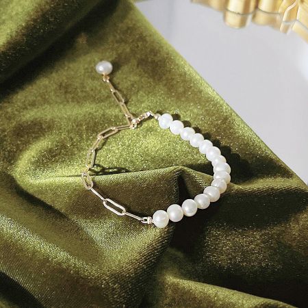 Full set of 14k gold plated freshwater pearl bracelets arranged on a soft green velvet background.