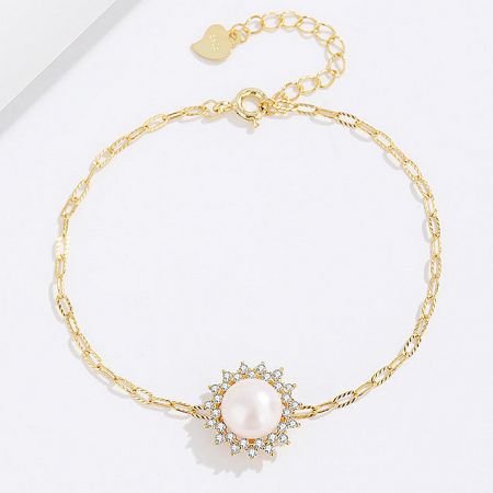 Close-up of the gold bracelet with a brilliant pearl and diamond-like zircon pendant.