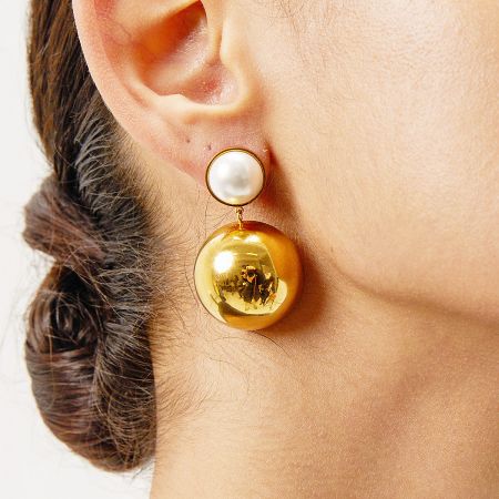 Close-up view of a woman wearing the gold and pearl hemisphere dome earring.