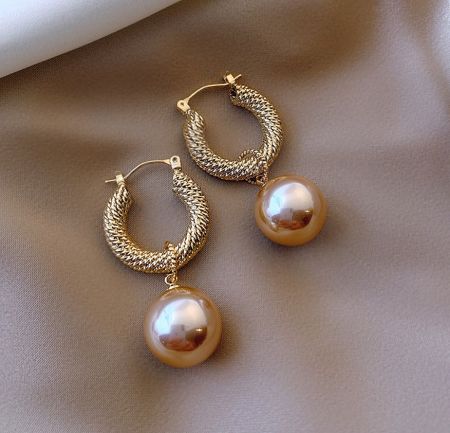 Detailed close-up of the gold-plated twisted hoop and pearl cap on the vintage huggie earrings.