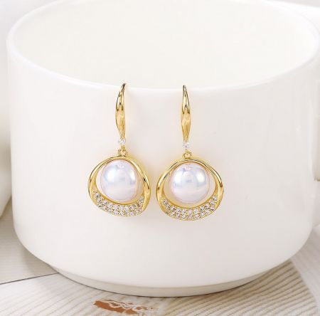 Side profile of the gold pearl drop earrings, highlighting the fish hook closure.