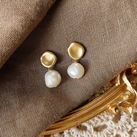 A pair of 14k gold baroque pearl earrings with a matte finish, showcasing their elegant design.