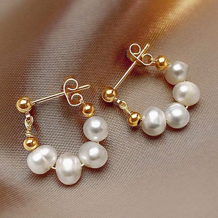 Full view of the pair of gold and pearl earrings, emphasizing their natural luster and elegant design.