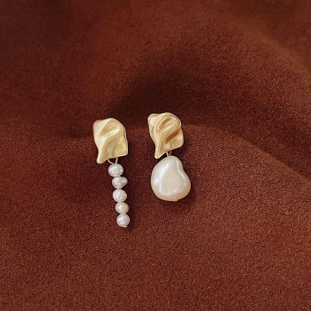 A pair of gold earrings with a leaf-like design and dangling baroque pearl elements.