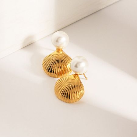 Angled shot of the gold and pearl stud earrings.