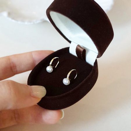 The pearl hook earrings presented in a luxurious velvet jewelry box, perfect for gifting.