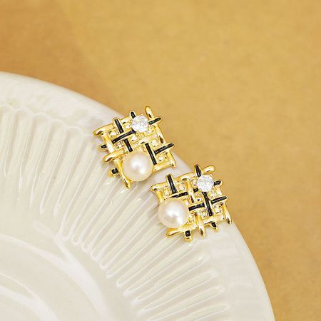 Product shot of the gold and black enamel earrings displayed on a decorative plate.
