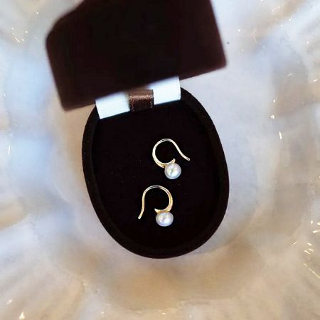 Detailed product view of the 925 sterling silver pearl earrings on a black display stand.
