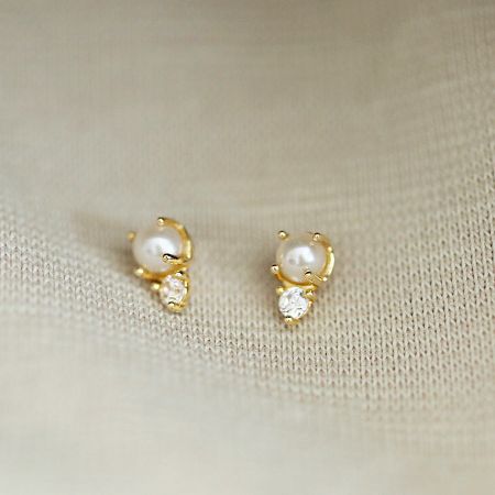 A delicate gold stud earring featuring a single pearl and a sparkling cubic zirconia accent.