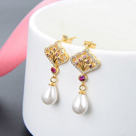 A stylish shot of the gold-plated pearl and gemstone earrings.