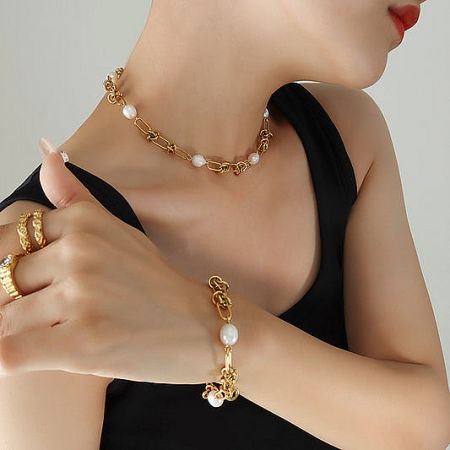 A stylish gold jewelry set with pearls, including a necklace and matching bracelet.