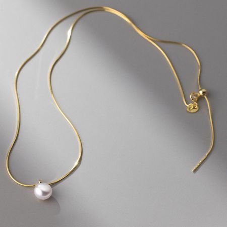 Full view of the gold single pearl choker necklace, highlighting its lustrous finish.