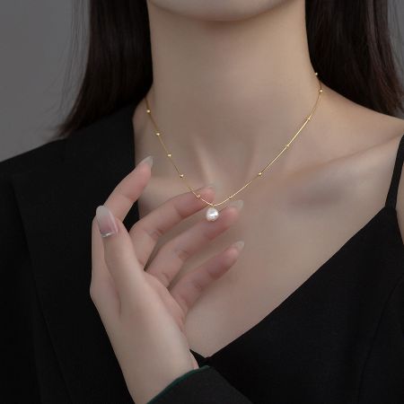 Close-up of the gold vintage baroque pearl necklace, highlighting the lustrous pearl and delicate chain.