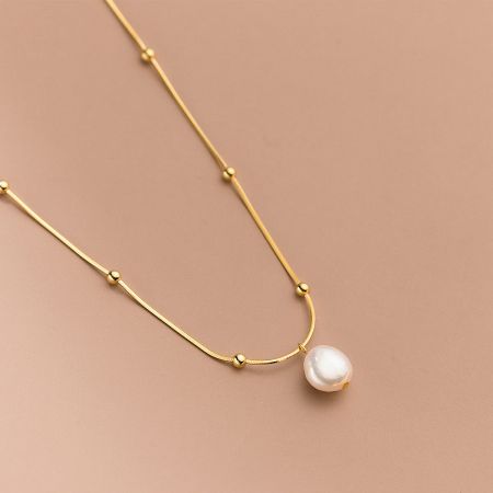 Another perspective of the gold baroque pearl necklace, emphasizing the unique shape of the natural pearl.