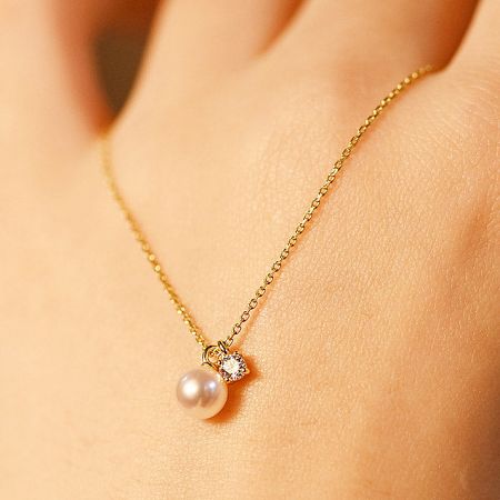 Side view of the gold pearl and zircon necklace.