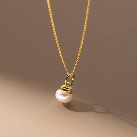 Close-up view of the gold-plated necklace with its lustrous single pearl pendant.