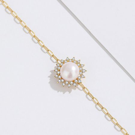 Detailed view of the pearl and zircon pendant on the delicate gold paper clip chain.