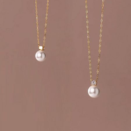 Comparison shot of two gold pearl necklaces showcasing the fine details of the pendant.