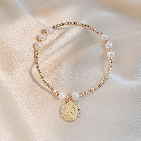 Close-up of the Queen Elizabeth II coin pendant on the gold and pearl bracelet.