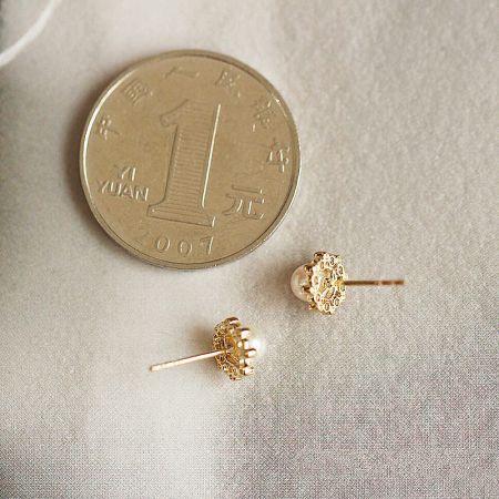 Size comparison of the gold pearl stud earrings next to a coin.