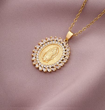 Detailed view of a custom gold pendant necklace with an engraved religious figure and surrounding gemstones.