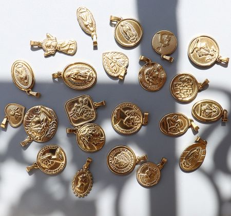 Diverse collection of intricately designed gold religious charms for custom jewelry manufacturing.