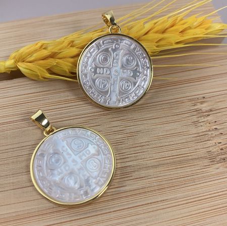 Custom Mother Of Pearl Carving Jess Mary Charms - Custom Mother of Pearl Jess Mary Charms by JR Fashion Accessories, featuring two gold-framed pendants with intricate carvings on a wooden surface.