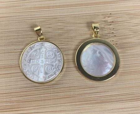 Close-up view of two custom gold pendants, one with a silver medallion and the other with a lustrous mother-of-pearl stone.