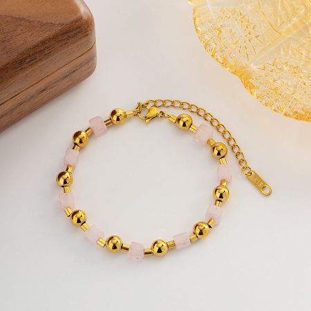 Detailed close-up of the gold and pink stone bead bracelet, showing the clasp and extension chain.