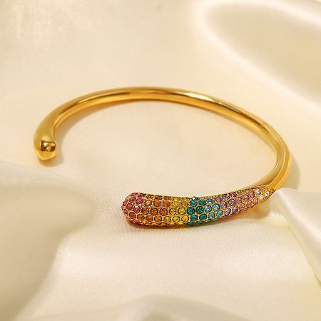Close-up of the gold cuff bangle featuring a row of vibrant, rainbow-colored cubic zirconia stones.