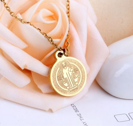 Detailed shot of the gold religious pendant with a central figure and Latin text.