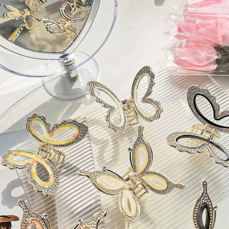 A display of various gold hair clips, including butterfly and heart shapes with rhinestone details.
