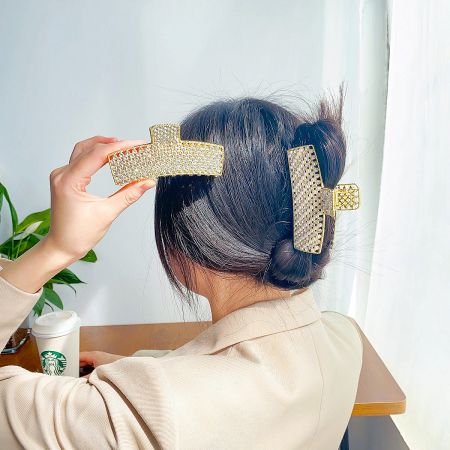 A model showcasing the elegant gold rhinestone hair clip, holding her hair up effortlessly.