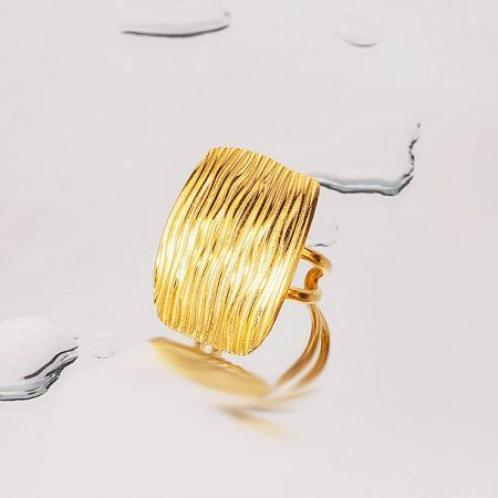 Close-up of a gold-finished ring with a detailed ribbed texture.